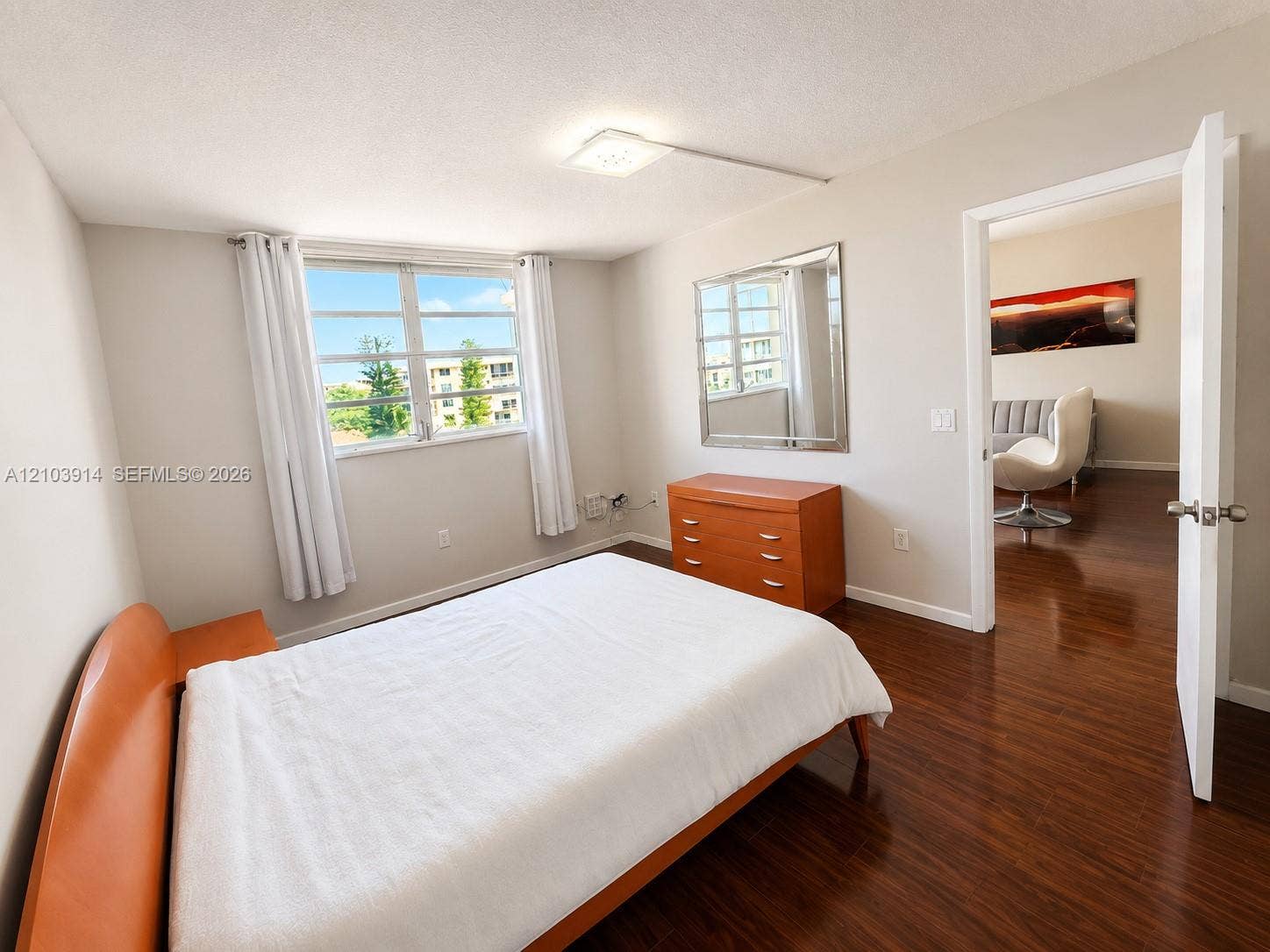 Neutral-toned interior featuring wood-finish flooring, a wall-mounted flush-mount light fixture, and large dual-pane windows