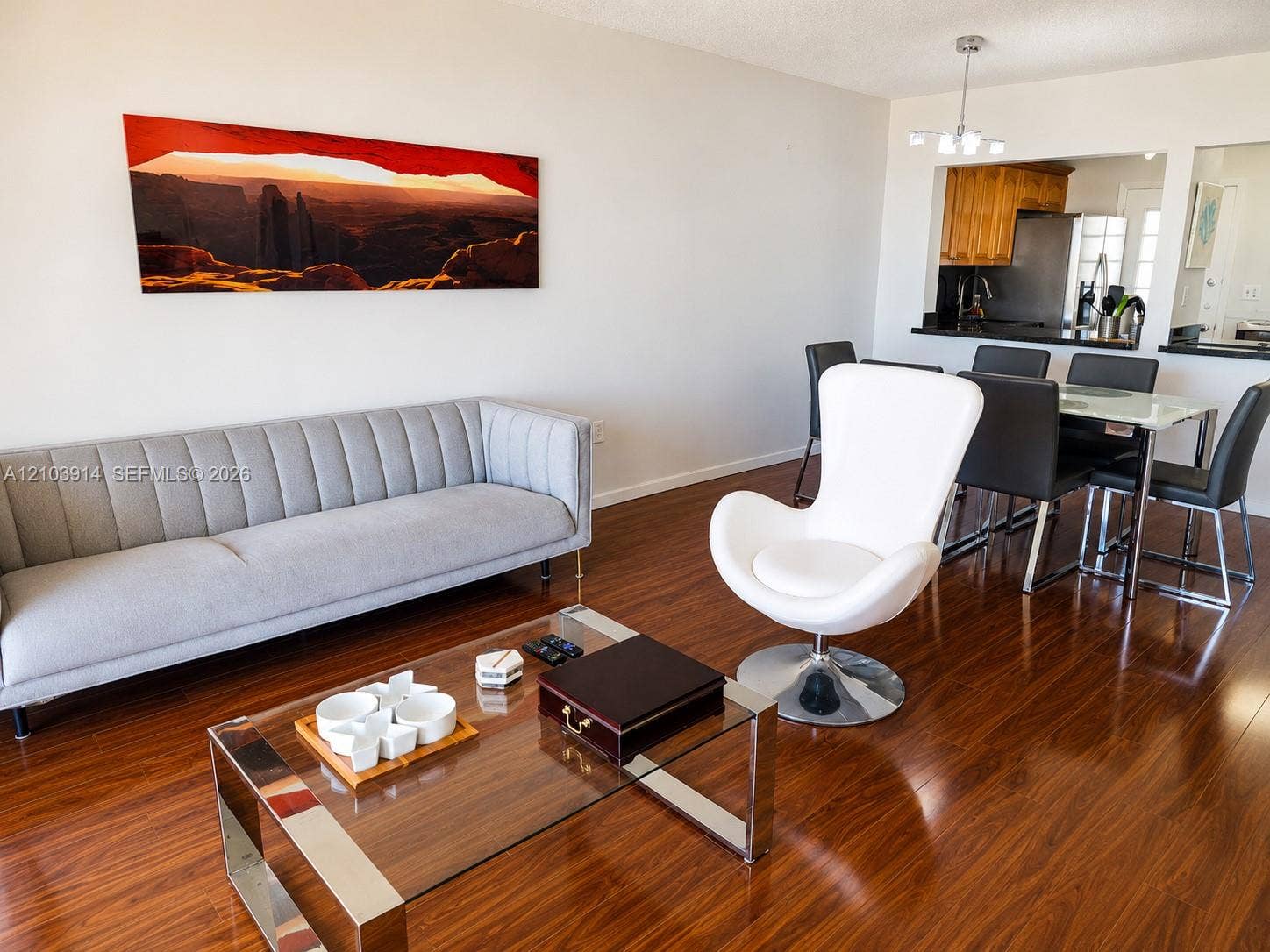 Wood-finish flooring throughout, pass-through kitchen opening, and multi-light chandelier