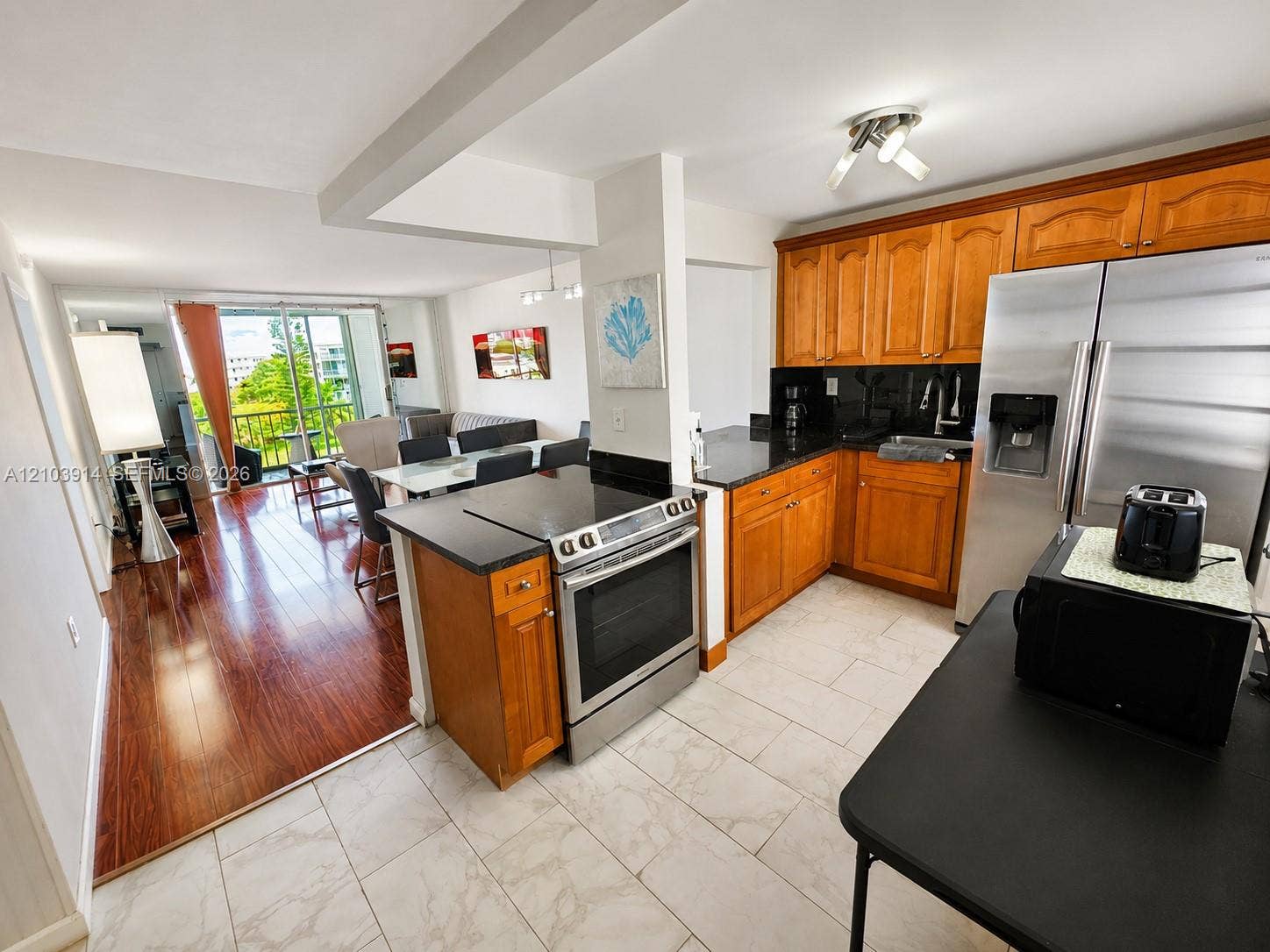 Kitchen featuring wood cabinetry, stone countertops, and stainless steel appliances, paired with wood-finish flooring and tile flooring