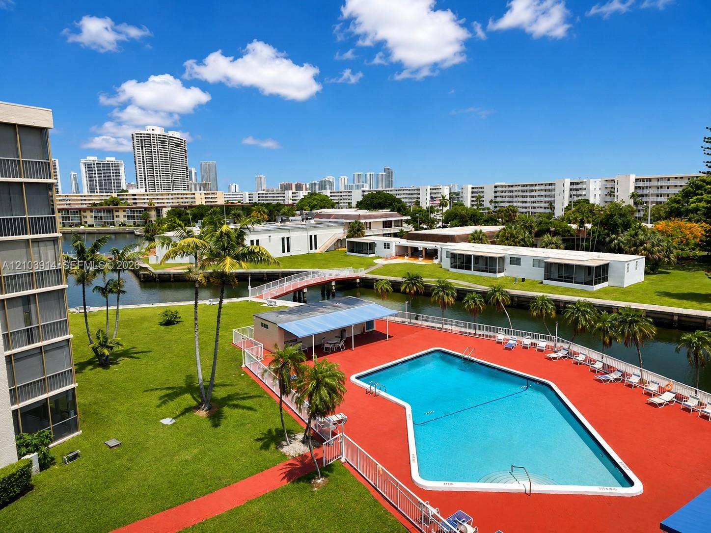 Swimming pool with a paved deck, canal frontage, pedestrian bridge, and landscaped grounds