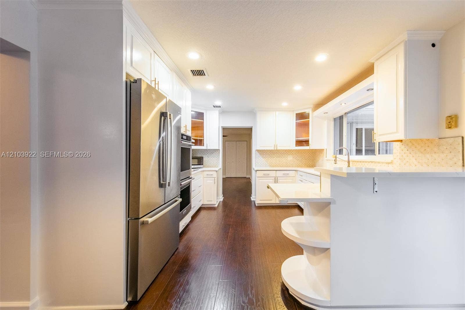 Kitchen featuring wood-finish flooring, white cabinetry, stainless steel appliances, and recessed lighting