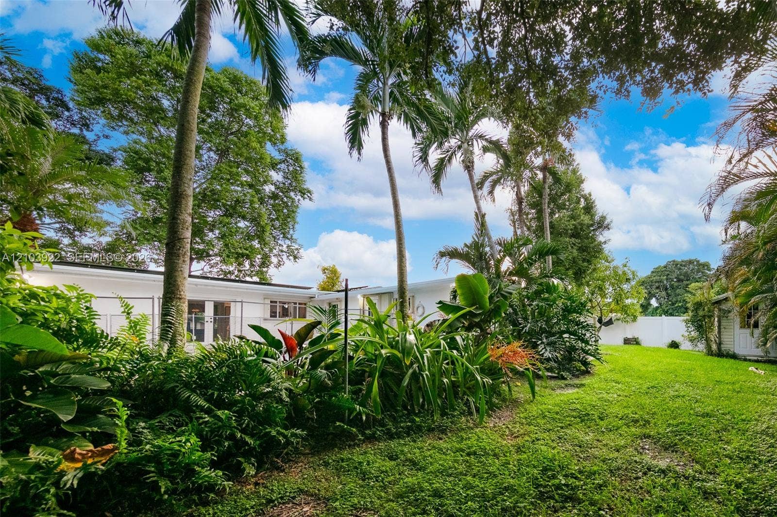 Expansive lawn area with mature trees and lush tropical landscaping