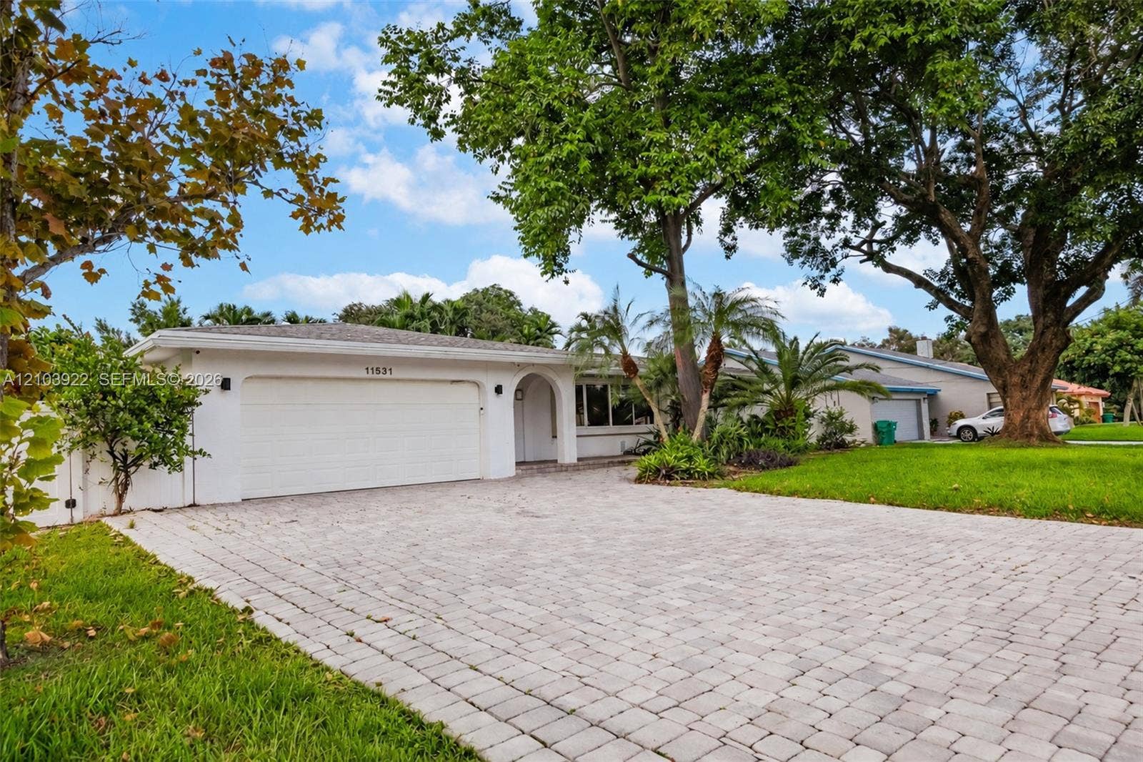 Paved driveway leading to a white stucco exterior with an arched entry