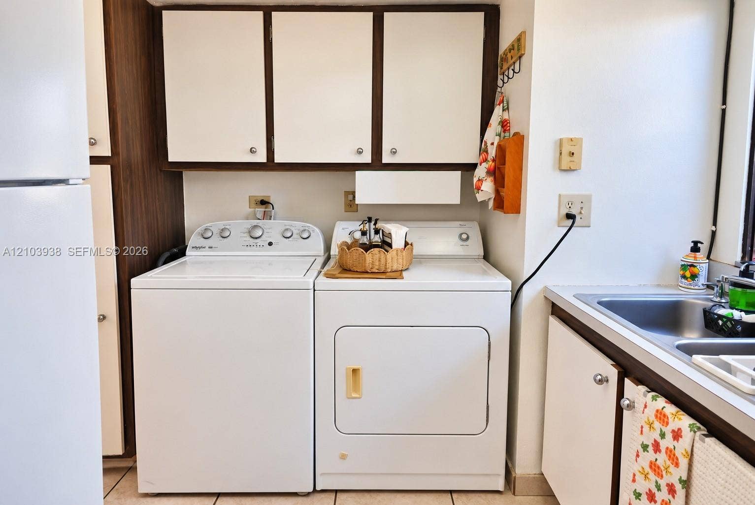 11335 SW 71st Lane, Miami, FL 33173 Laundry area featuring overhead cabinetry, built-in dual-basin stainless steel sink, and ceramic tile flooring