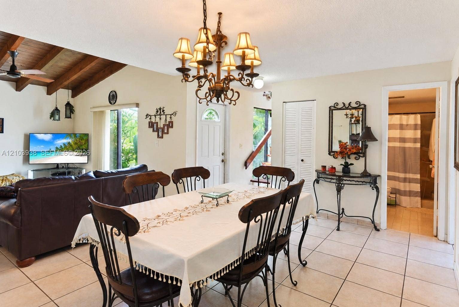 11335 SW 71st Lane, Miami, FL 33173 Dining area featuring tile flooring, a multi-arm metal chandelier, and a vaulted ceiling with exposed wood beams