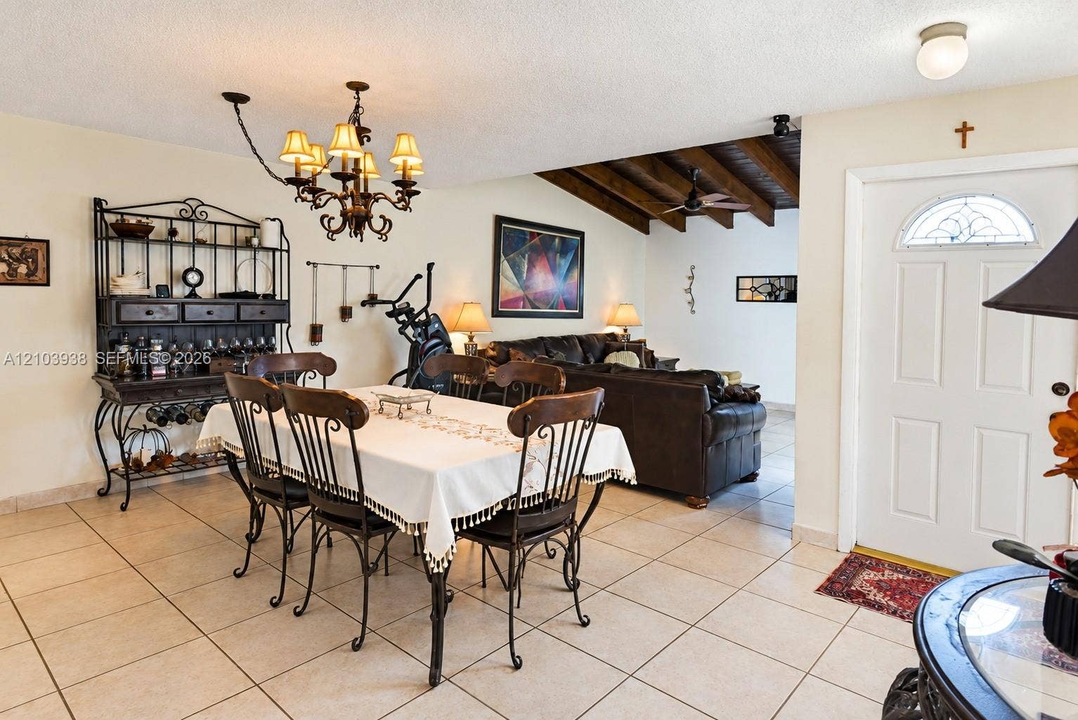 11335 SW 71st Lane, Miami, FL 33173 Ceramic tile flooring, exposed wood-beam ceiling, multi-light iron chandelier, and exterior entry door with an arched glass insert