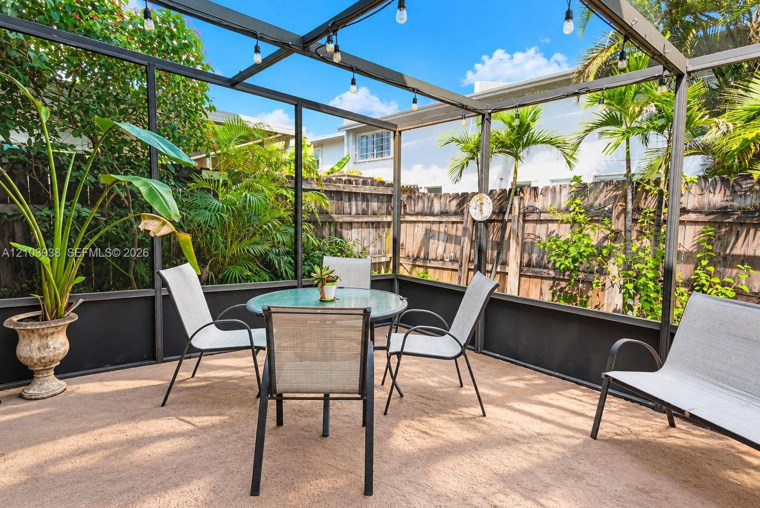 11335 SW 71st Lane, Miami, FL 33173 Screened-in patio featuring a concrete floor, metal framing, built-in string lighting, and wood privacy fencing