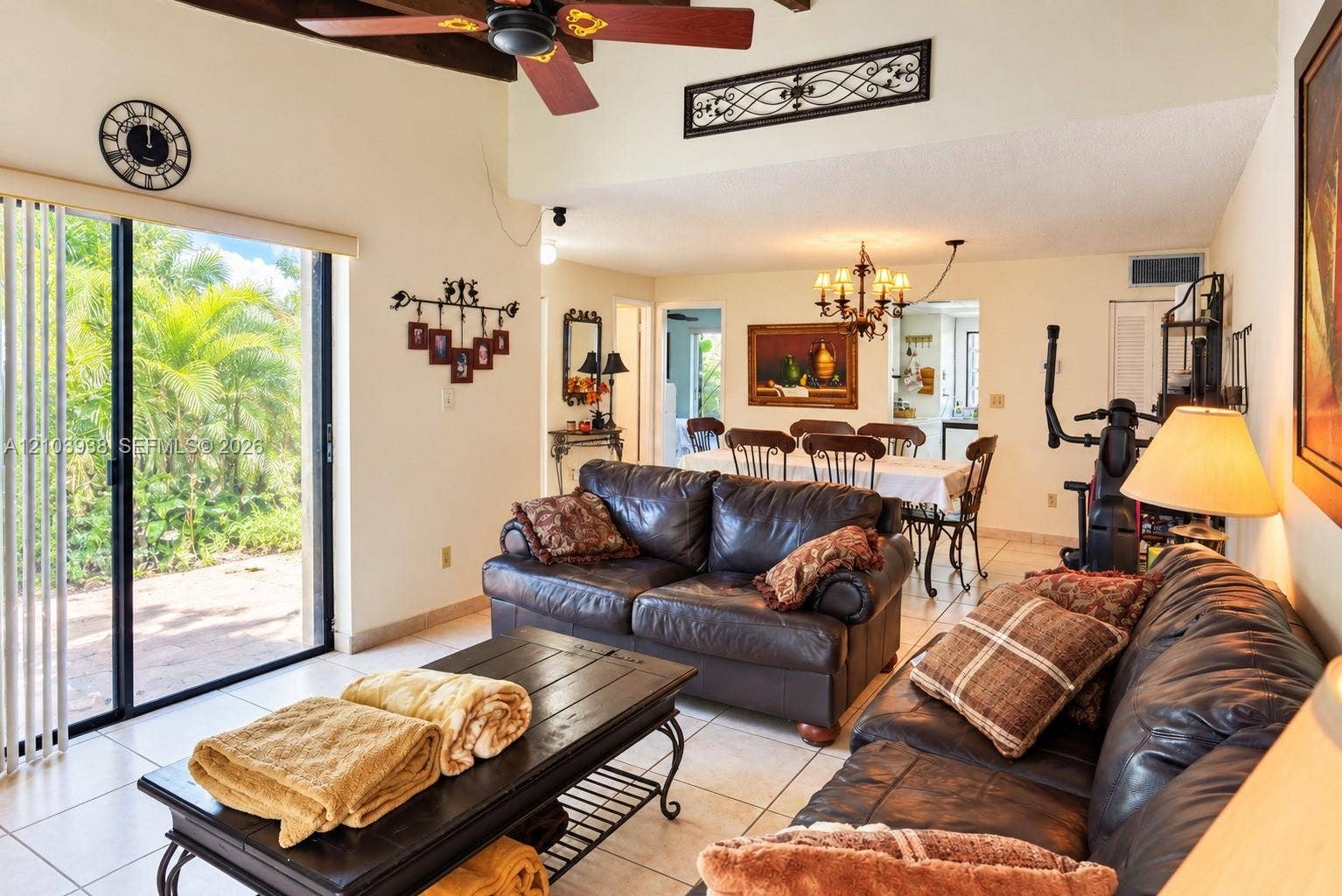11335 SW 71st Lane, Miami, FL 33173 Open-concept interior featuring vaulted ceilings with exposed wood beams, ceiling fan, ceramic tile flooring, and large sliding glass doors