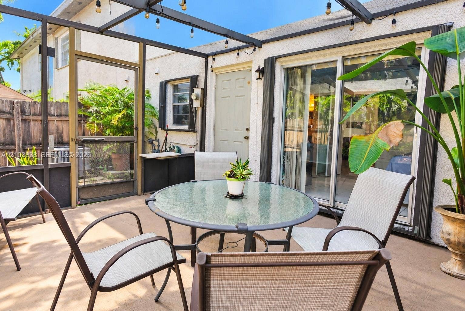 11335 SW 71st Lane, Miami, FL 33173 Screened-in patio featuring a concrete floor, dark metal structural framing, integrated string lighting, and sliding glass entry doors