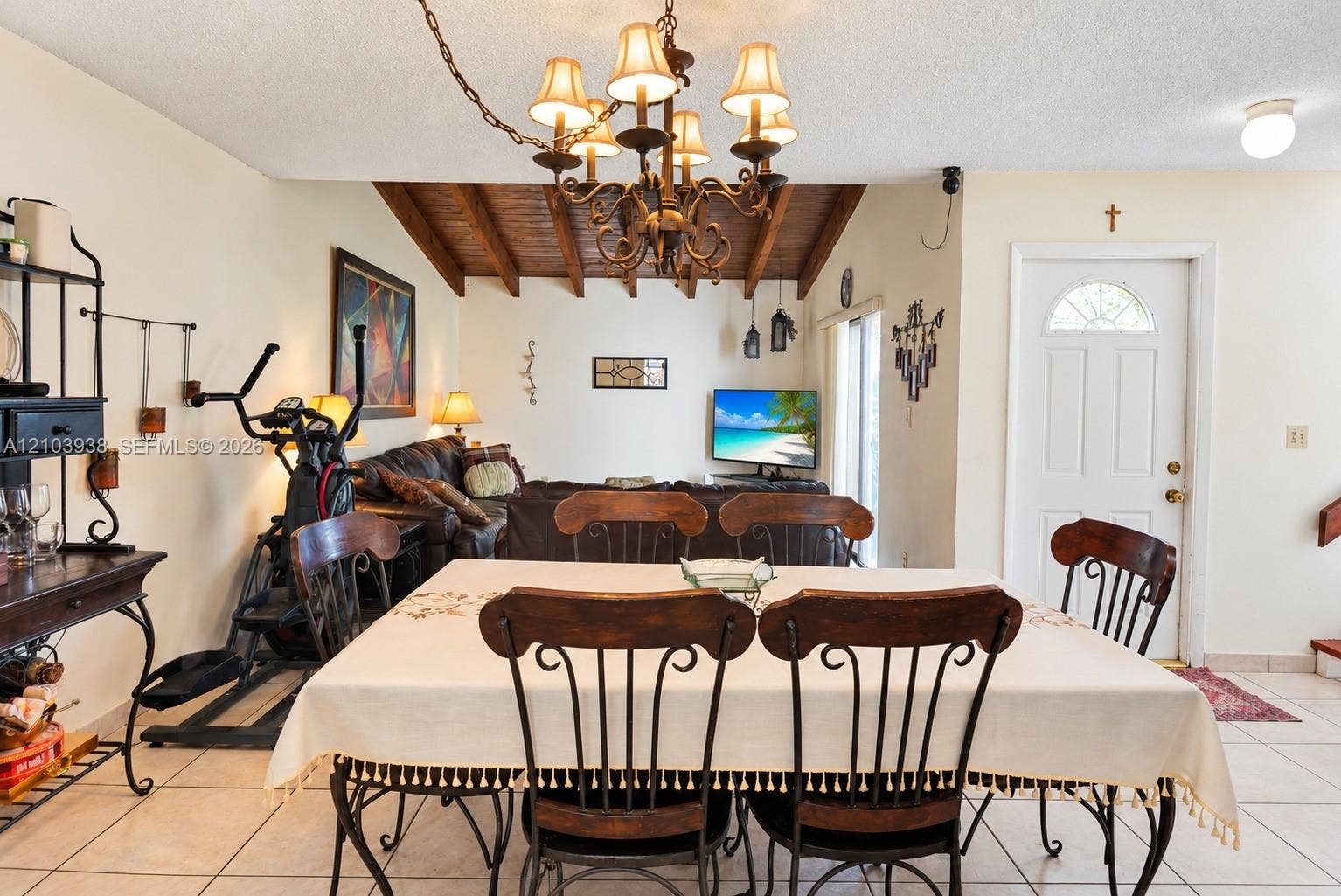 11335 SW 71st Lane, Miami, FL 33173 Vaulted ceiling with exposed wood beams, multi-arm chandelier, and ceramic tile flooring