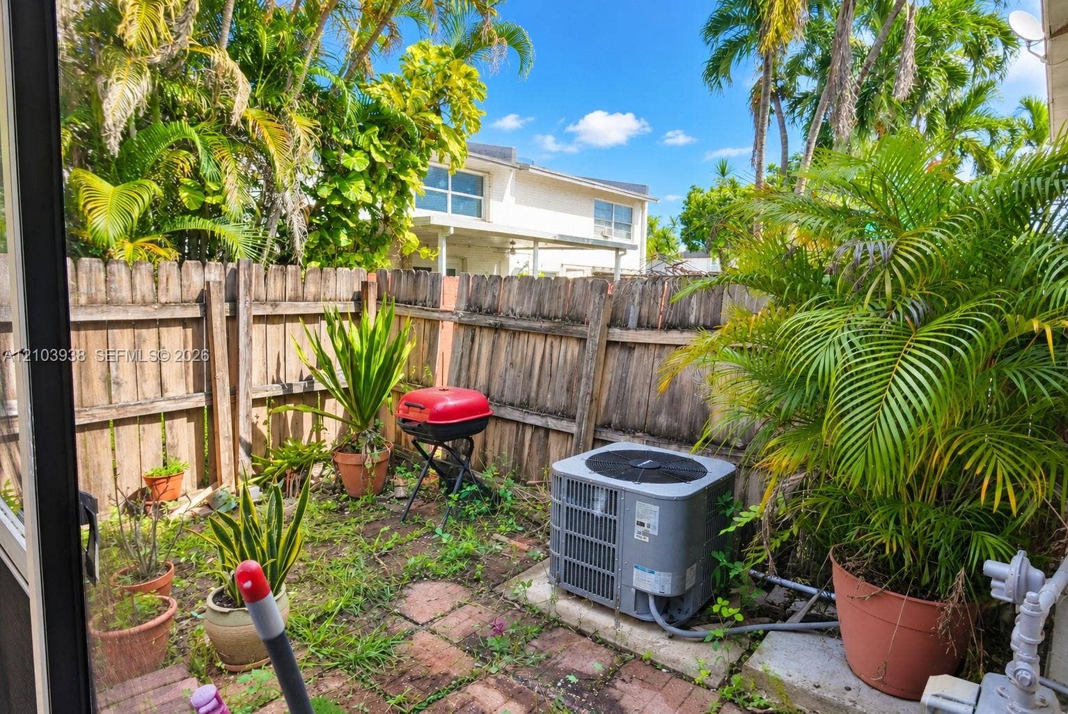 11335 SW 71st Lane, Miami, FL 33173 Private outdoor area featuring brick pavers, mature palm trees, and perimeter wood fencing