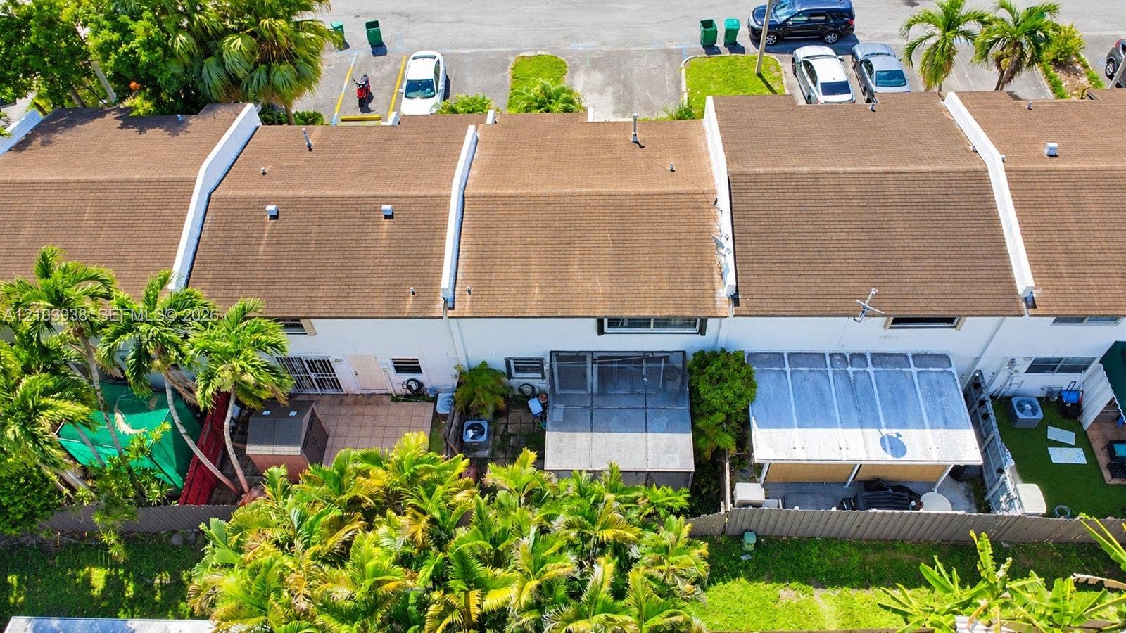 11335 SW 71st Lane, Miami, FL 33173 Aerial perspective of townhomes featuring shingled rooflines, exterior patios, screened-in enclosures, and lush perimeter landscaping