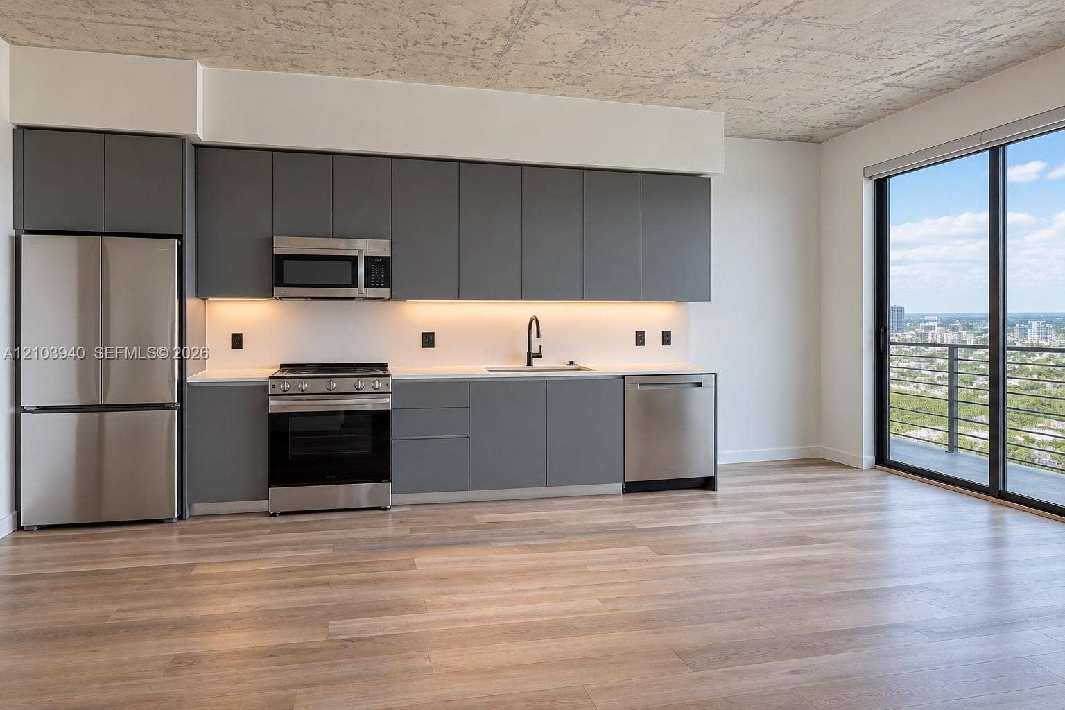 307 SW 5th Street, #2610, Fort Lauderdale, Fort Lauderdale, FL 33315 Modern kitchen featuring matte grey flat-panel cabinetry, stainless steel appliances, white stone-finish countertops, exposed concrete-texture ceiling, and floor-to-ceiling glass sliding doors