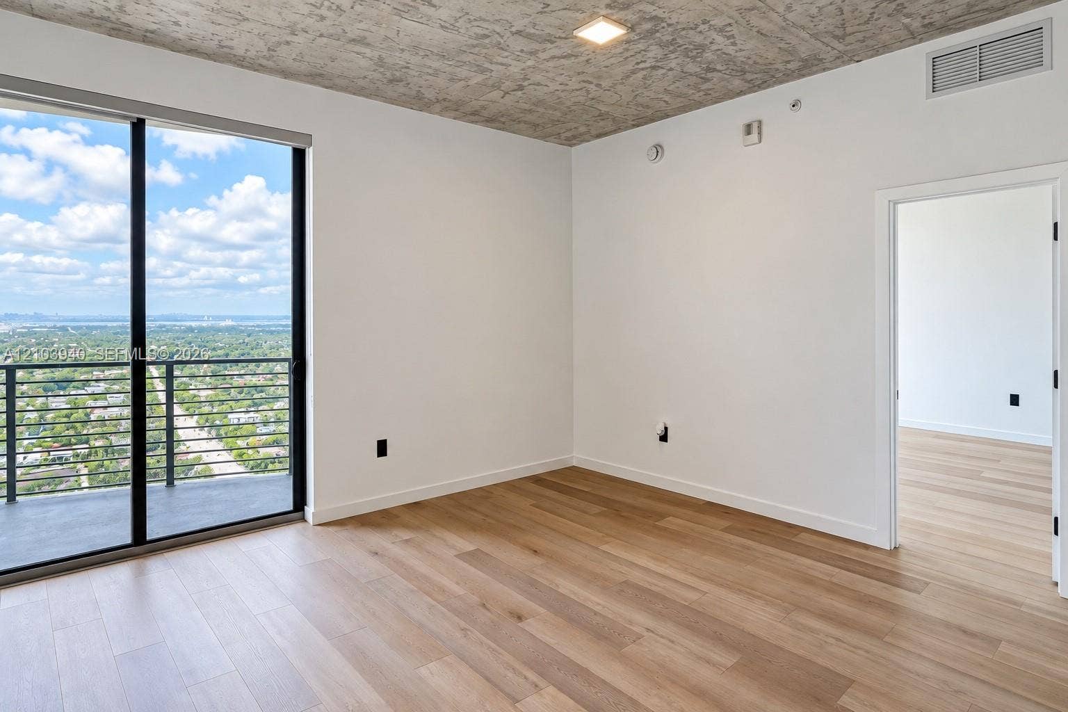 307 SW 5th Street, #2610, Fort Lauderdale, Fort Lauderdale, FL 33315 Interior space featuring raw concrete ceiling, wood-finish flooring, floor-to-ceiling glass sliding door, and private balcony with metal railing