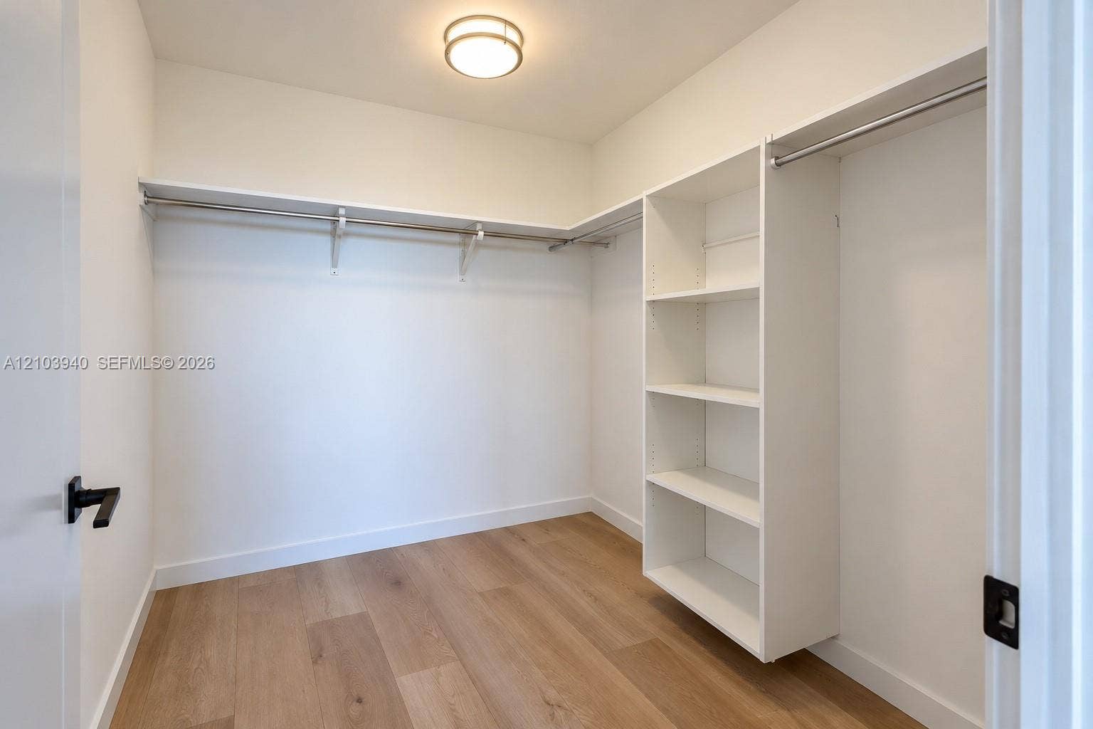 307 SW 5th Street, #2610, Fort Lauderdale, Fort Lauderdale, FL 33315 Walk-in closet featuring white built-in shelving, integrated metal hanging rods, wood-finish flooring, and a flush-mount ceiling light