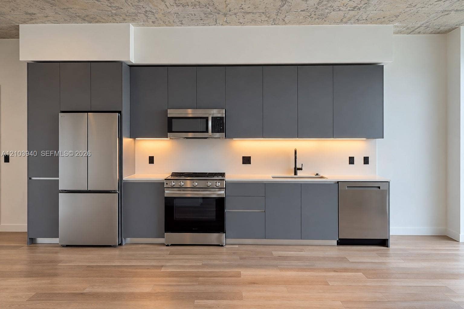 307 SW 5th Street, #2610, Fort Lauderdale, Fort Lauderdale, FL 33315 Kitchen featuring matte grey flat-panel cabinetry, light-toned countertops, stainless steel appliances, under-cabinet lighting, and wood-finish flooring