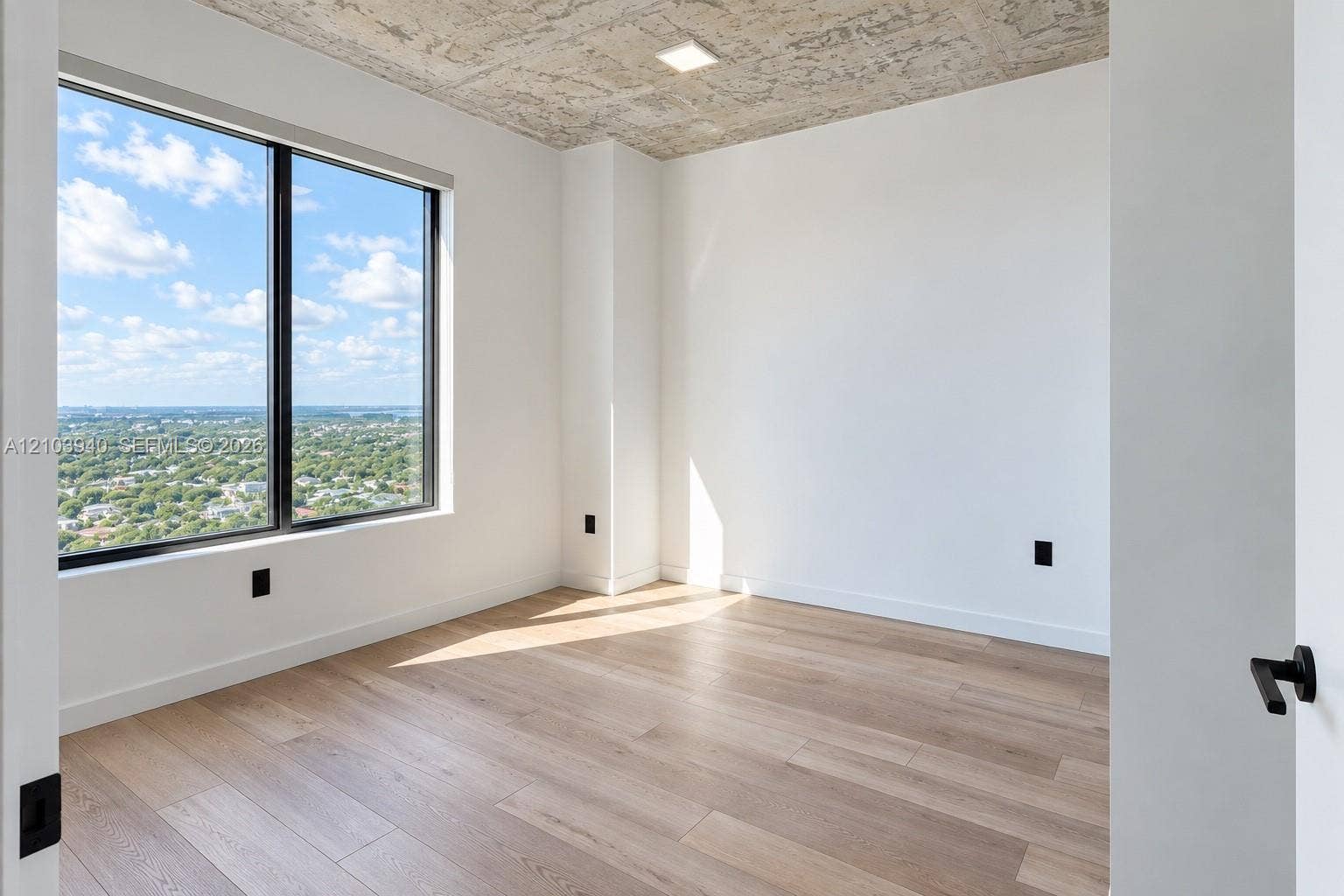 307 SW 5th Street, #2610, Fort Lauderdale, Fort Lauderdale, FL 33315 Room featuring wood-finish flooring, an exposed concrete ceiling, large-format window with dark trim, and white walls