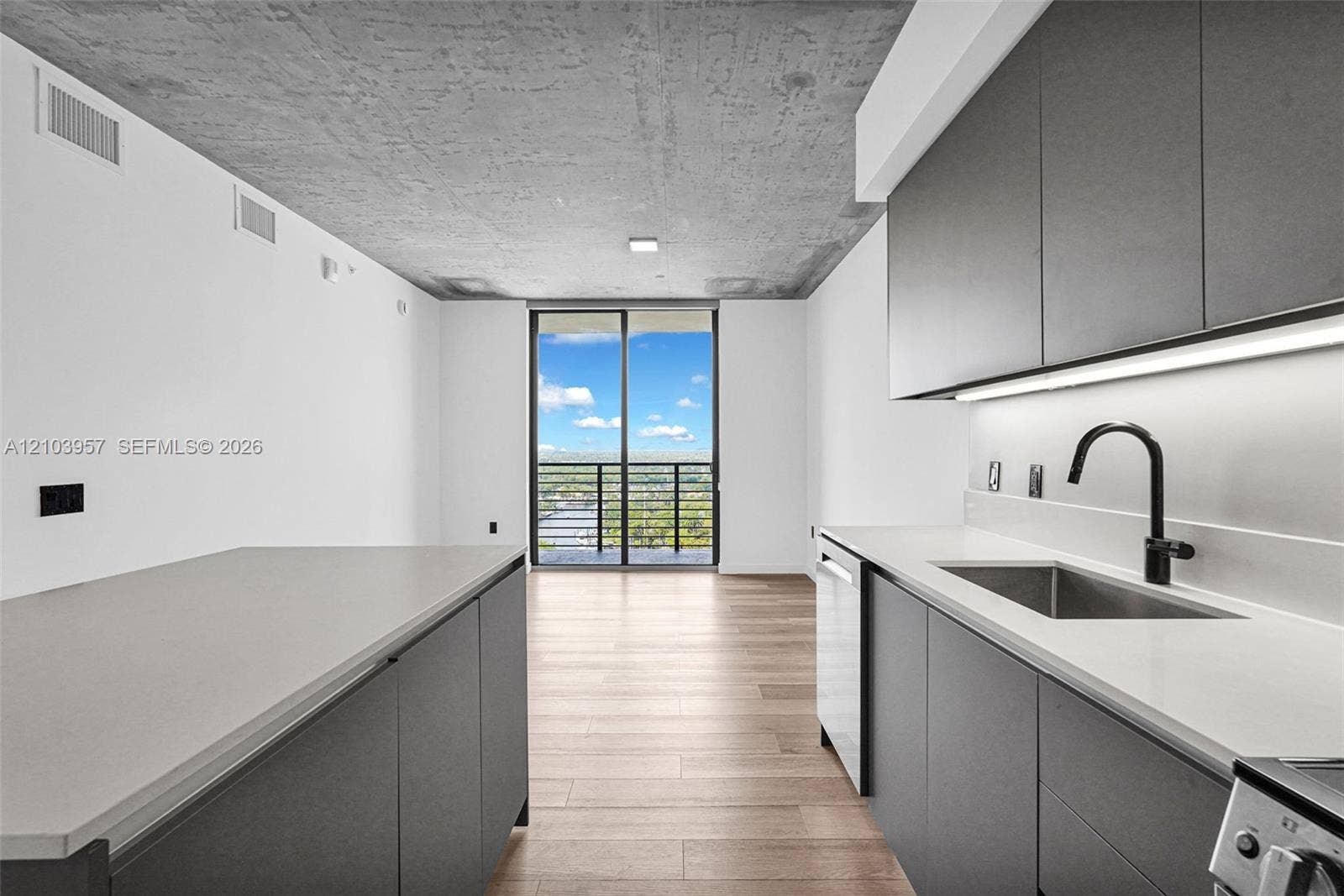 307 SW 5th Street, #0, Fort Lauderdale, Fort Lauderdale, FL 33315 Exposed concrete ceiling, wood-finish flooring, full-height sliding glass doors, contemporary flat-panel cabinetry, and matte black kitchen faucet