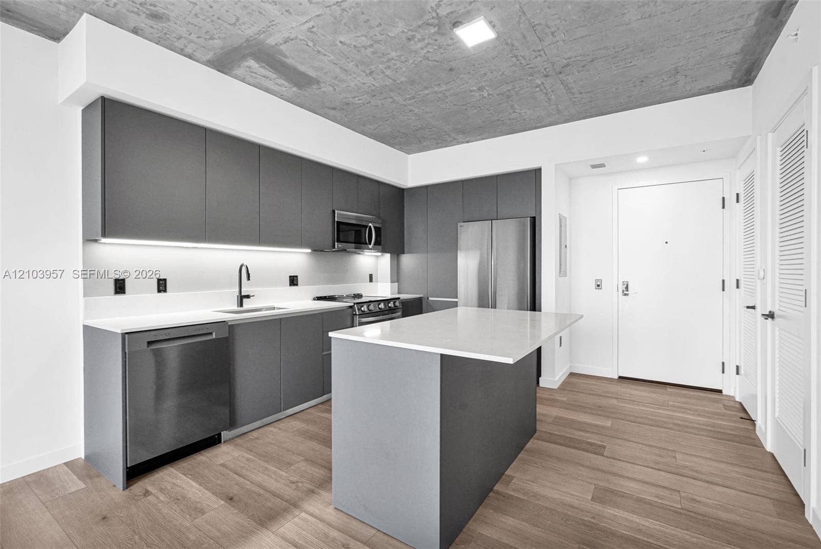 307 SW 5th Street, #0, Fort Lauderdale, Fort Lauderdale, FL 33315 Kitchen featuring wood-finish flooring, an island with a light-toned countertop, stainless steel appliances, and sleek gray cabinetry with under-cabinet lighting