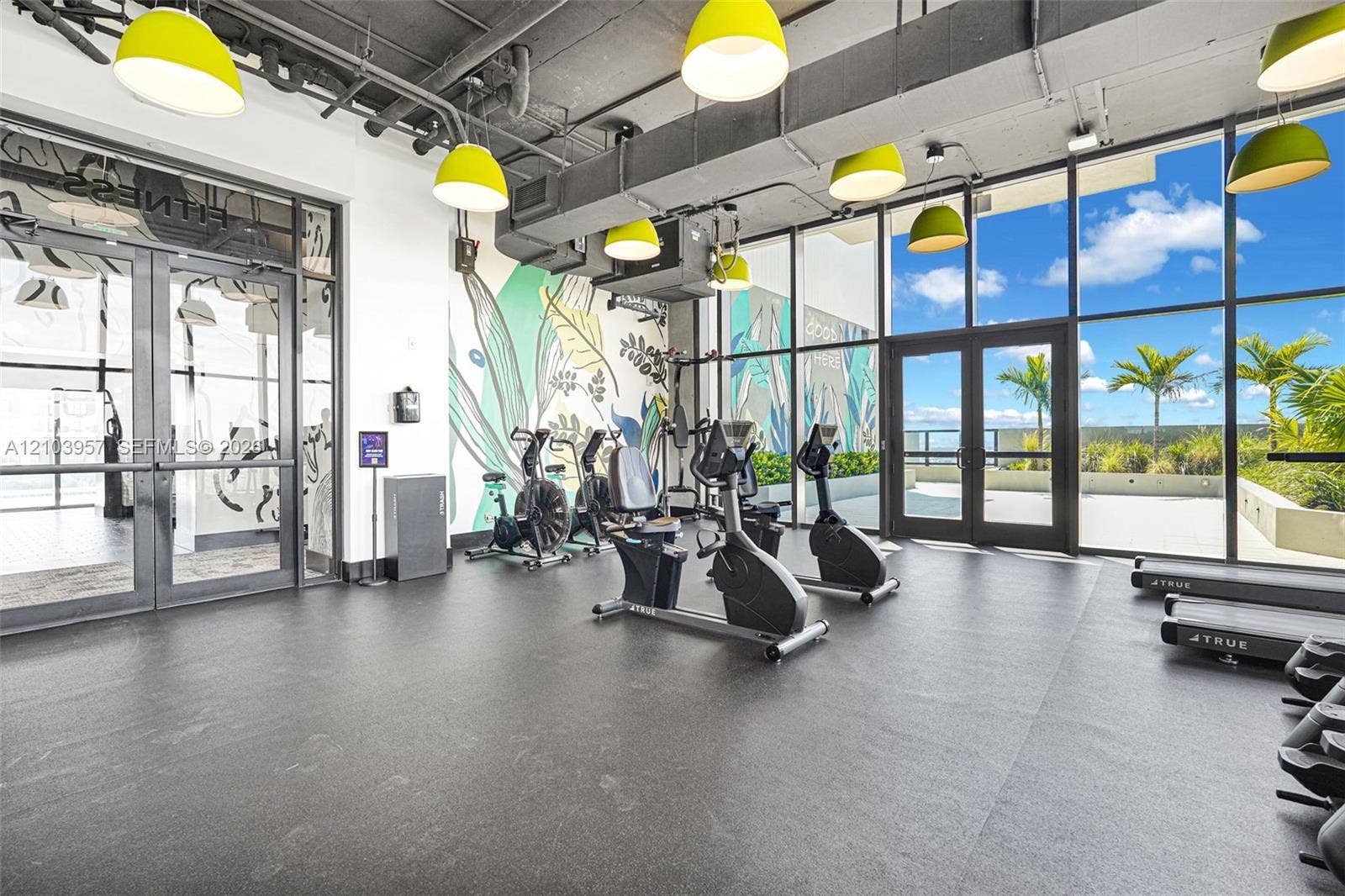 307 SW 5th Street, #0, Fort Lauderdale, Fort Lauderdale, FL 33315 Expansive fitness room featuring a full wall of floor-to-ceiling windows, direct outdoor access, contemporary pendant lighting, and a decorative accent wall