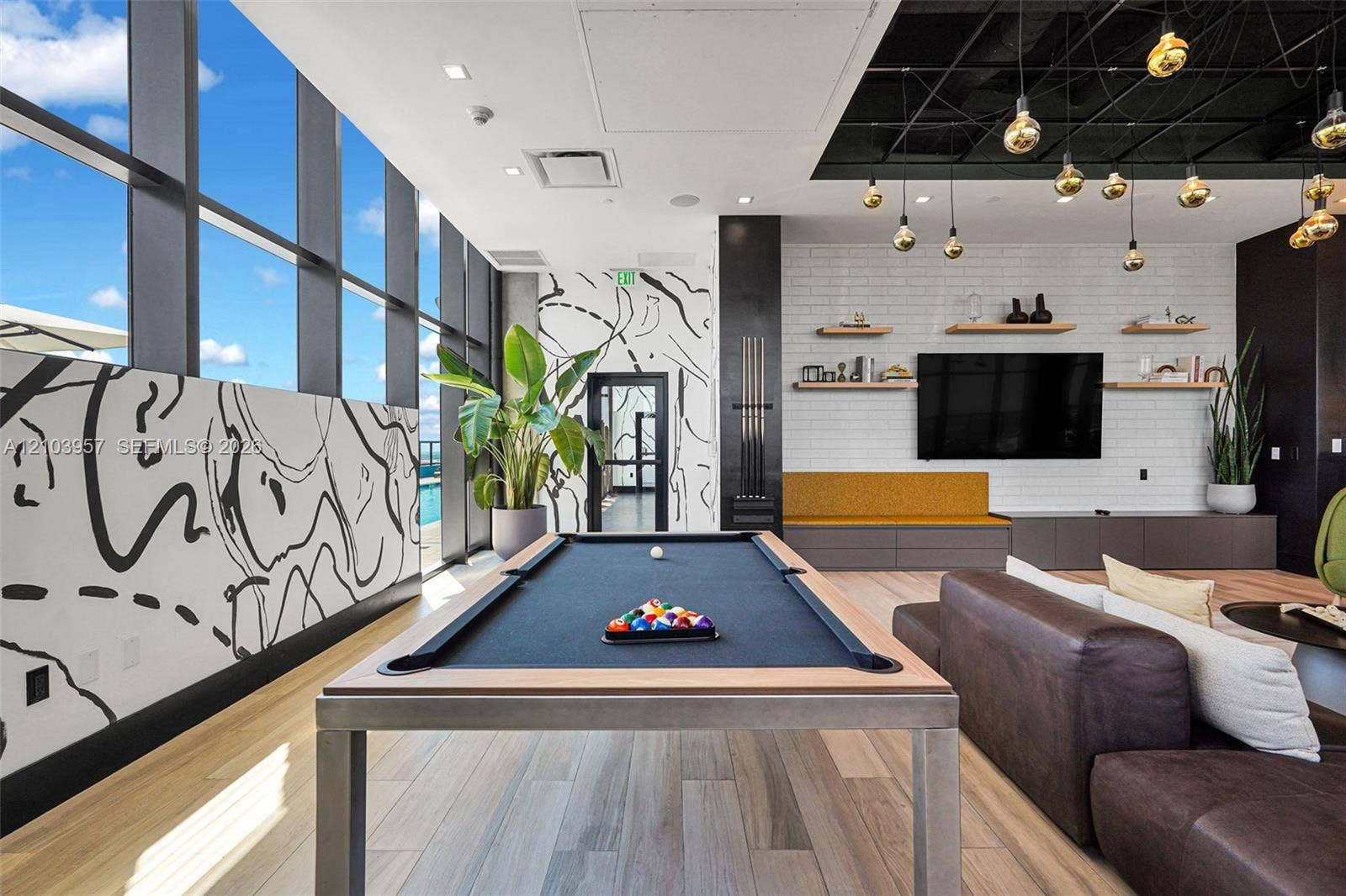 307 SW 5th Street, #0, Fort Lauderdale, Fort Lauderdale, FL 33315 Floor-to-ceiling windows, wood-finish flooring, white brick accent wall, built-in shelving, and recessed lighting