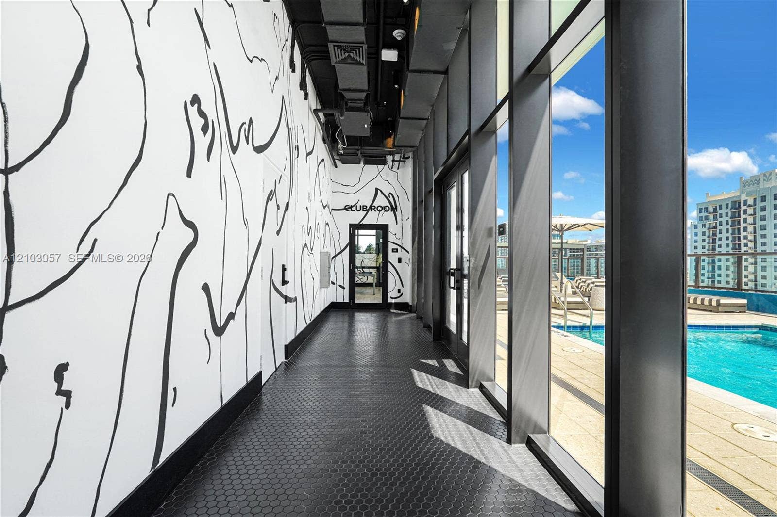 307 SW 5th Street, #0, Fort Lauderdale, Fort Lauderdale, FL 33315 Hallway featuring patterned wall treatment, hexagonal tile flooring, and floor-to-ceiling windows overlooking an outdoor pool and distant buildings