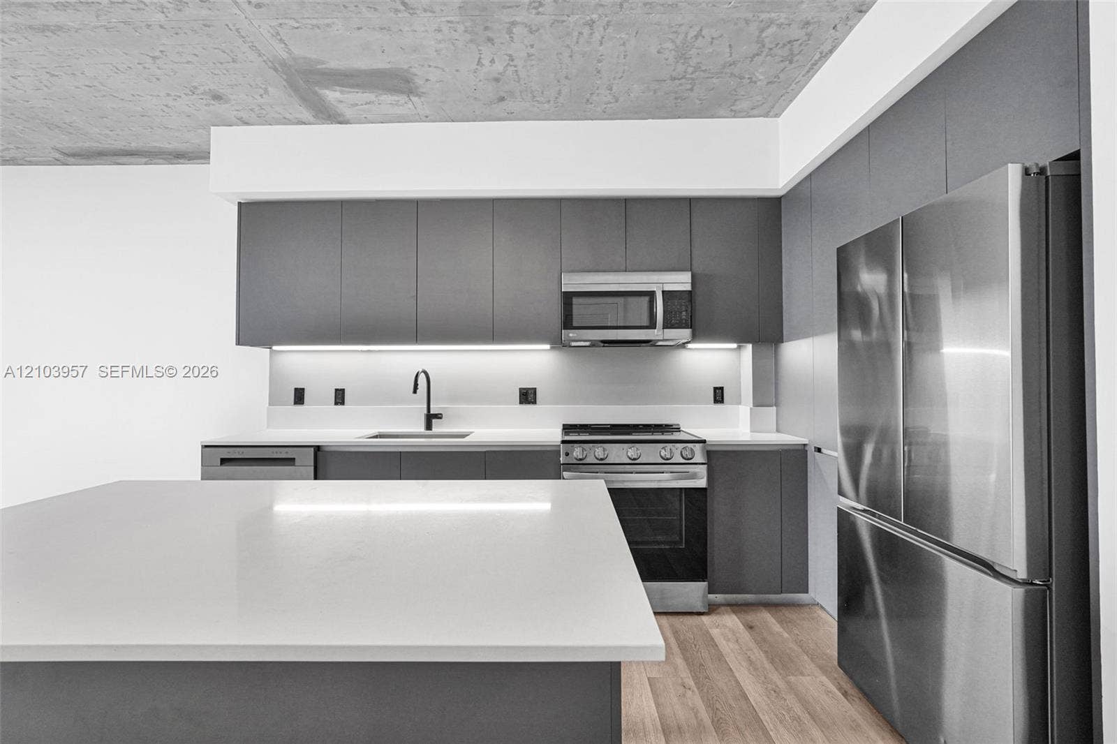 307 SW 5th Street, #0, Fort Lauderdale, Fort Lauderdale, FL 33315 Kitchen featuring flat-panel cabinetry, stainless steel appliances, quartz countertops, wood-finish flooring, and under-cabinet lighting