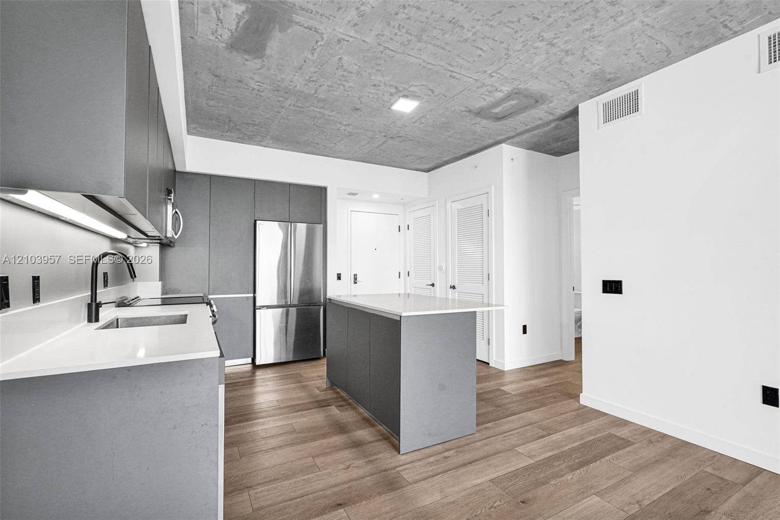 307 SW 5th Street, #0, Fort Lauderdale, Fort Lauderdale, FL 33315 Modern kitchen featuring a stainless steel refrigerator, matte black faucet, light wood-finish flooring, and a concrete-finish ceiling