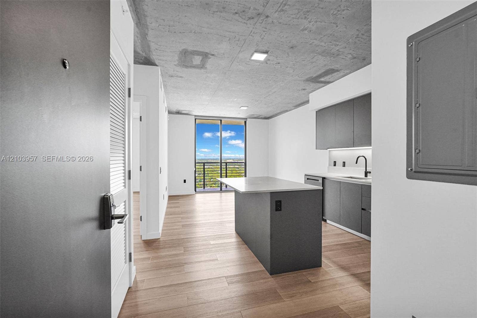 307 SW 5th Street, #0, Fort Lauderdale, Fort Lauderdale, FL 33315 Open concept living space featuring wood-finish flooring, a contemporary kitchen with dark cabinetry and a center island, and a concrete ceiling