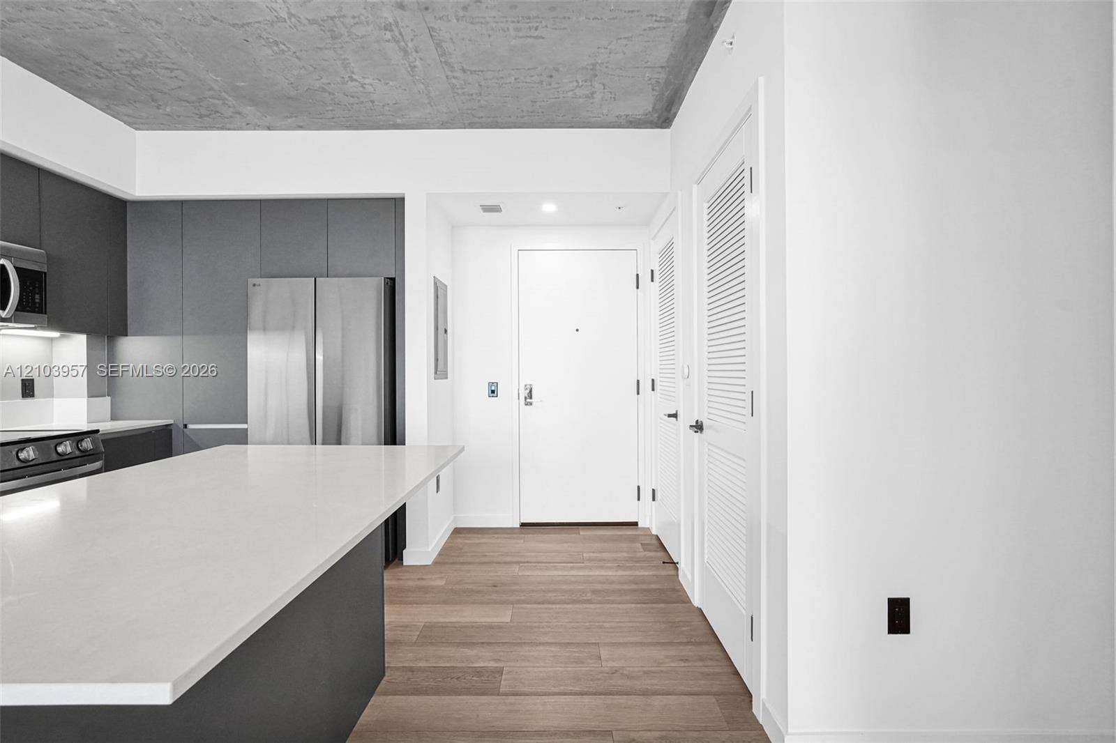 307 SW 5th Street, #0, Fort Lauderdale, Fort Lauderdale, FL 33315 Kitchen featuring a large island with a white countertop, dark flat-panel cabinetry, stainless steel appliances, and a wood-finish floor