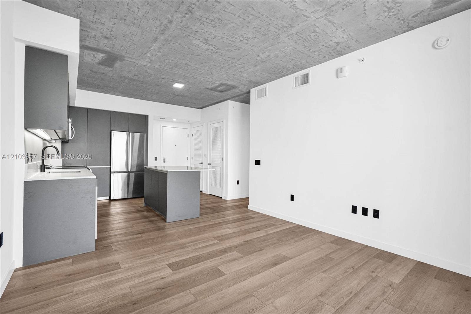 307 SW 5th Street, #0, Fort Lauderdale, Fort Lauderdale, FL 33315 Open-concept living area featuring wood-finish flooring, a textured concrete ceiling, and a modern kitchen with flat-panel cabinetry, a stainless steel refrigerator, and a kitchen island
