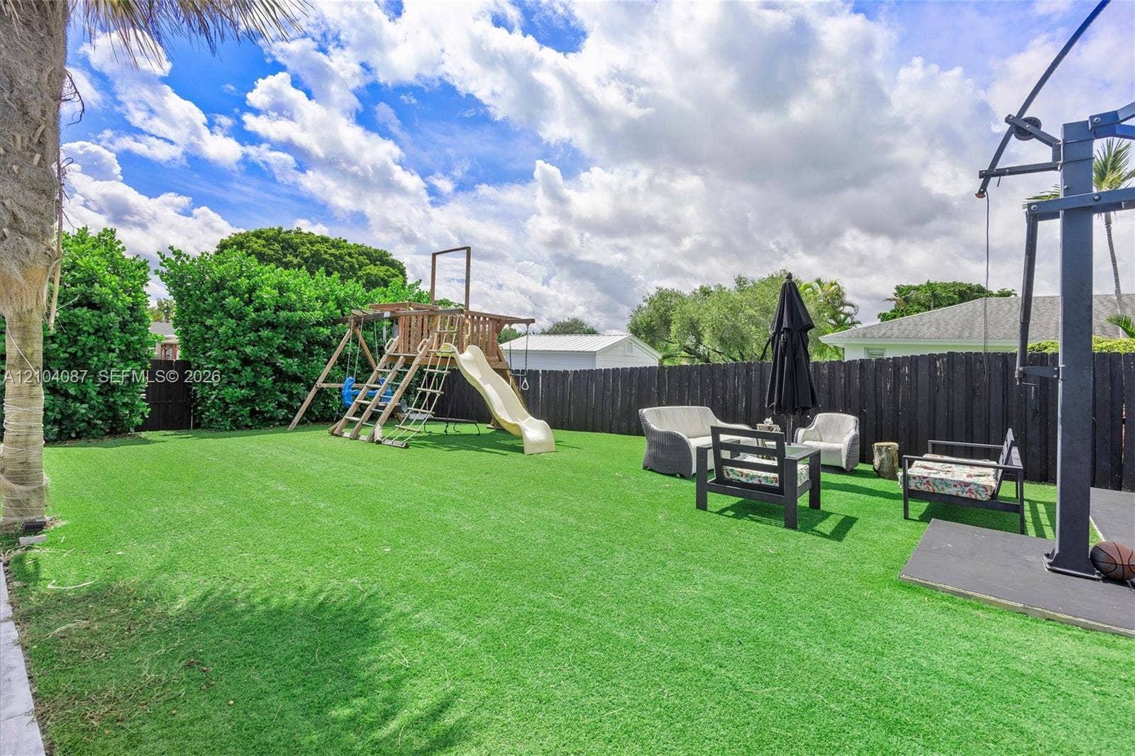 Expansive backyard featuring artificial turf, privacy fencing, and mature perimeter landscaping
