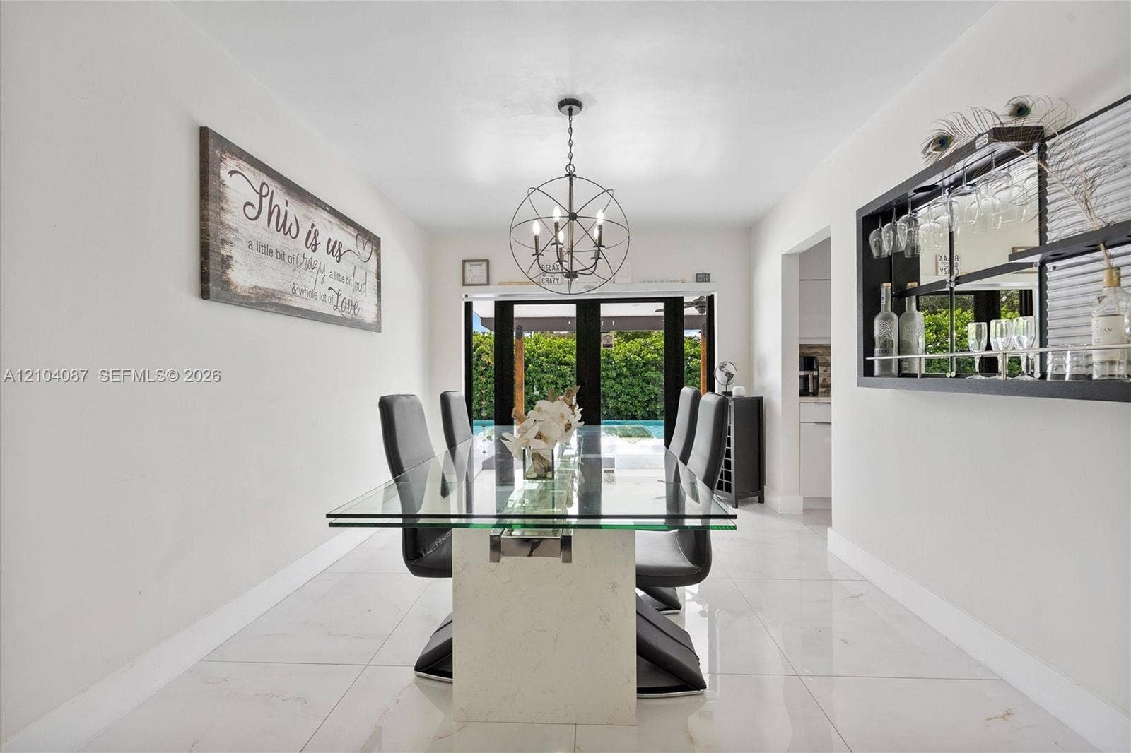 Recessed lighting, large format tile flooring, black multi-pane exterior doors, and a built-in wall bar with mirrored backing