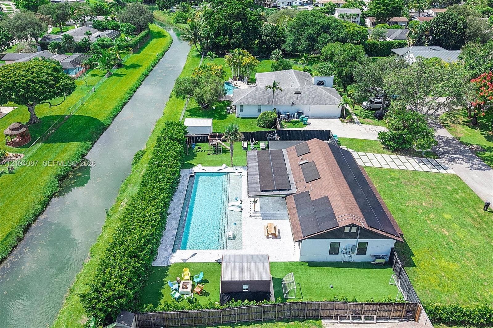 Exterior featuring a rectangular swimming pool, an expansive patio, and a dedicated artificial turf area