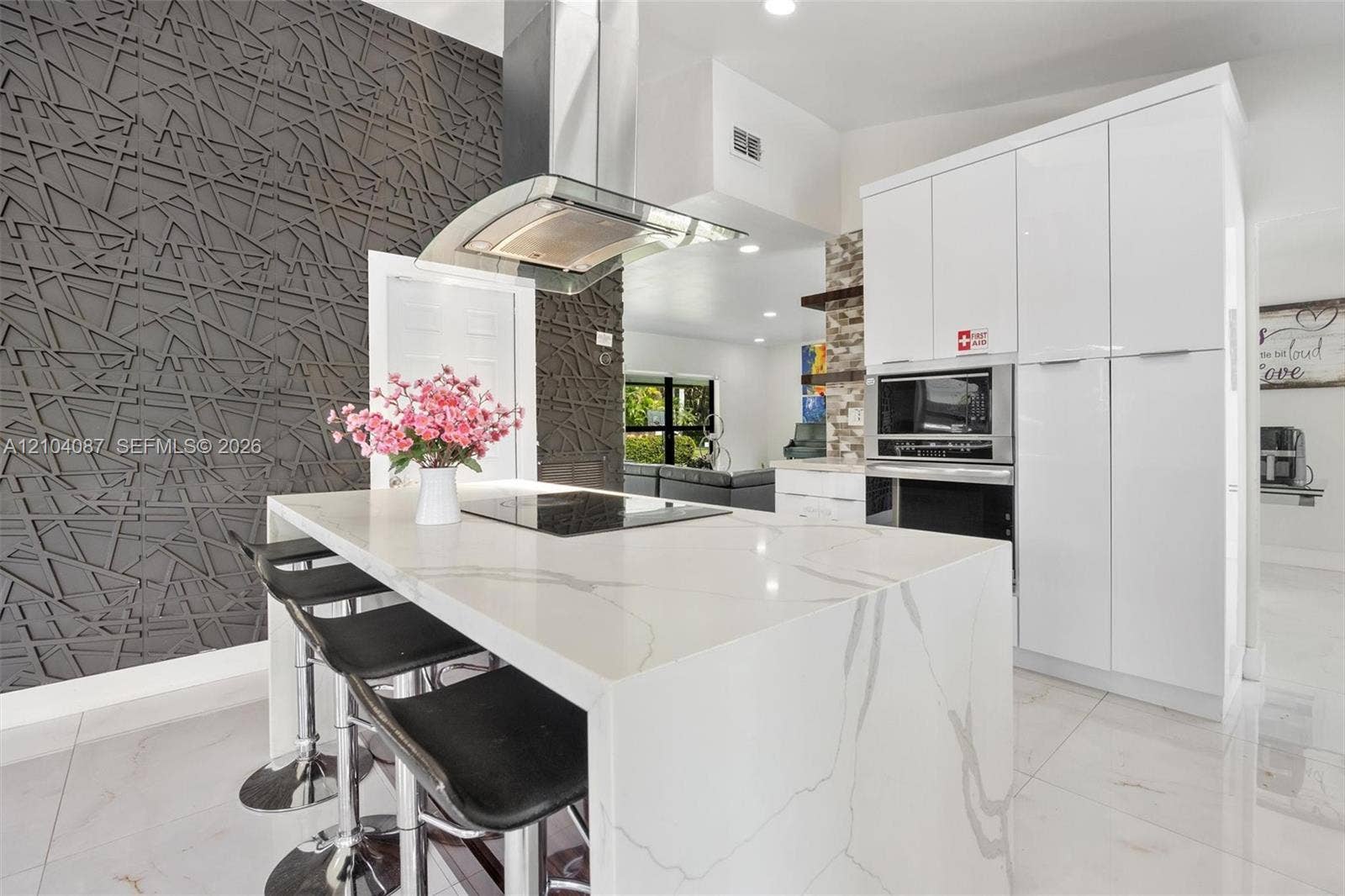 Kitchen island with waterfall countertop, integrated cooktop, and overhead range hood