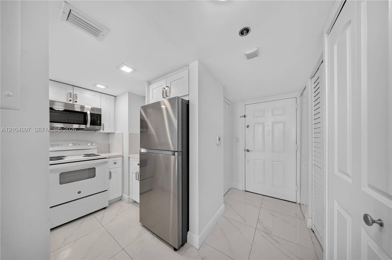 540 Brickell Key Drive, #916, Miami, Miami, FL 33131 Kitchen featuring white cabinetry, stainless steel refrigerator, white electric range, over-the-range microwave, and large-format tile flooring