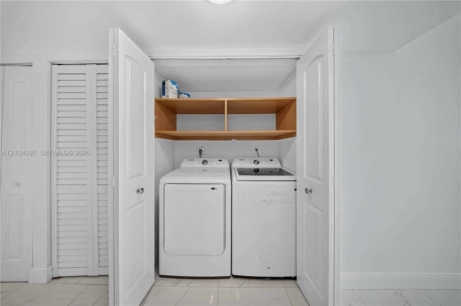 540 Brickell Key Drive, #916, Miami, Miami, FL 33131 Laundry area featuring wood-finish open shelving, white double-panel doors, and polished stone-finish flooring
