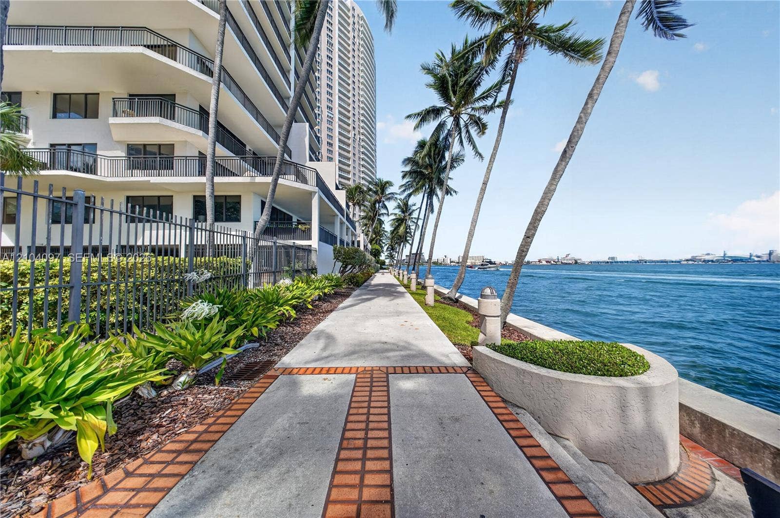 540 Brickell Key Drive, #916, Miami, Miami, FL 33131 Concrete paved promenade featuring brick-accented inlay, waterfront bulkhead, native landscaping, and mature palm trees