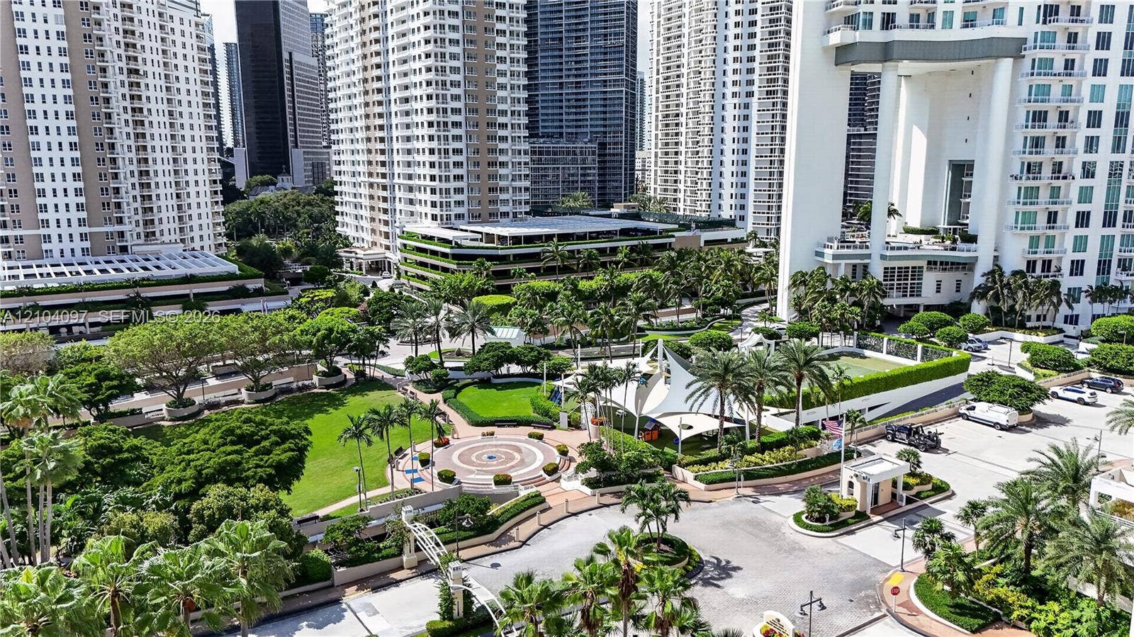 540 Brickell Key Drive, #916, Miami, Miami, FL 33131 Elevated aerial perspective featuring a landscaped urban plaza, manicured green space, paved pathways, mature palm trees, and a tensile shade structure