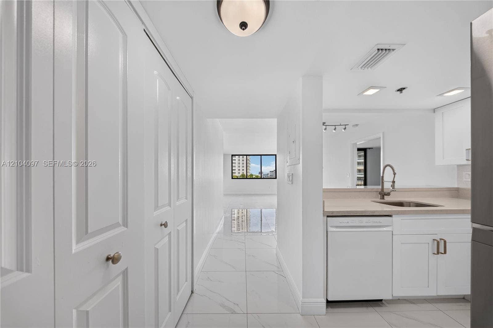 540 Brickell Key Drive, #916, Miami, Miami, FL 33131 White shaker-style cabinetry, neutral stone-finish countertops, stainless steel undermount sink with arched pull-down faucet, porcelain tile flooring, and floor-to-ceiling built-in closet storage