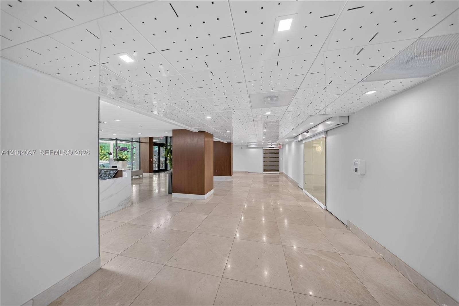 540 Brickell Key Drive, #916, Miami, Miami, FL 33131 Expansive foyer featuring large-format tile flooring, a geometric patterned drop ceiling with recessed lighting, wood-veneer columns, and a reception desk with stone-finish surfacing
