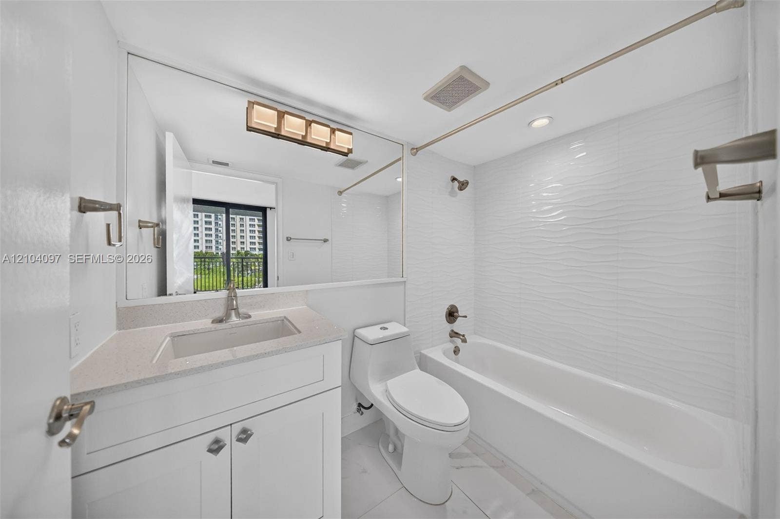 540 Brickell Key Drive, #916, Miami, Miami, FL 33131 Bathroom featuring a vanity with a stone-composite countertop, full-width mirror, tile flooring, and a tub with a textured tile surround