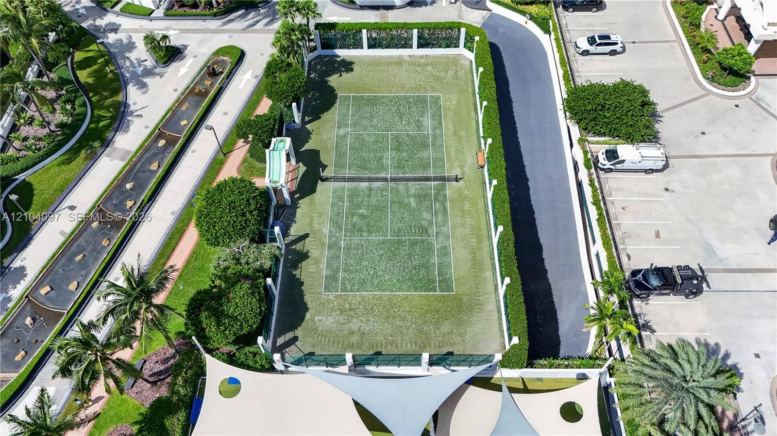 540 Brickell Key Drive, #916, Miami, Miami, FL 33131 Tennis court featuring a synthetic turf surface, perimeter fencing, and manicured hedge screening