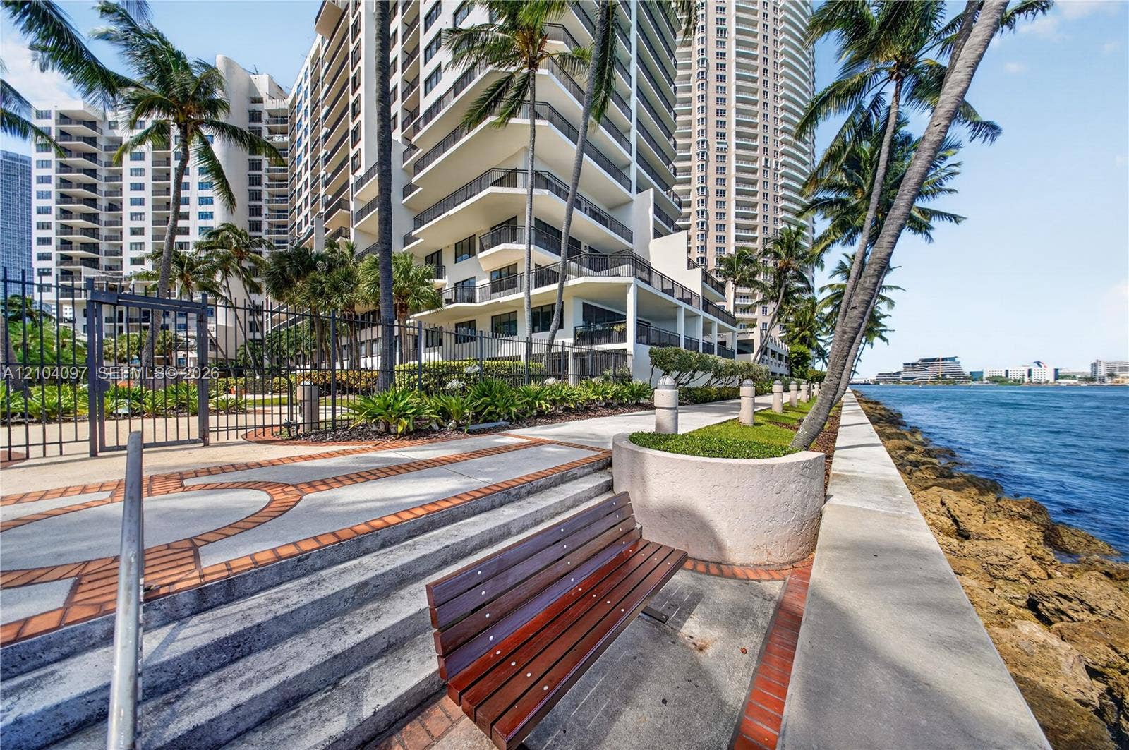 540 Brickell Key Drive, #916, Miami, Miami, FL 33131 Waterfront promenade featuring a paved walkway with brick accents, concrete retaining walls, integrated landscaping, and metal perimeter fencing