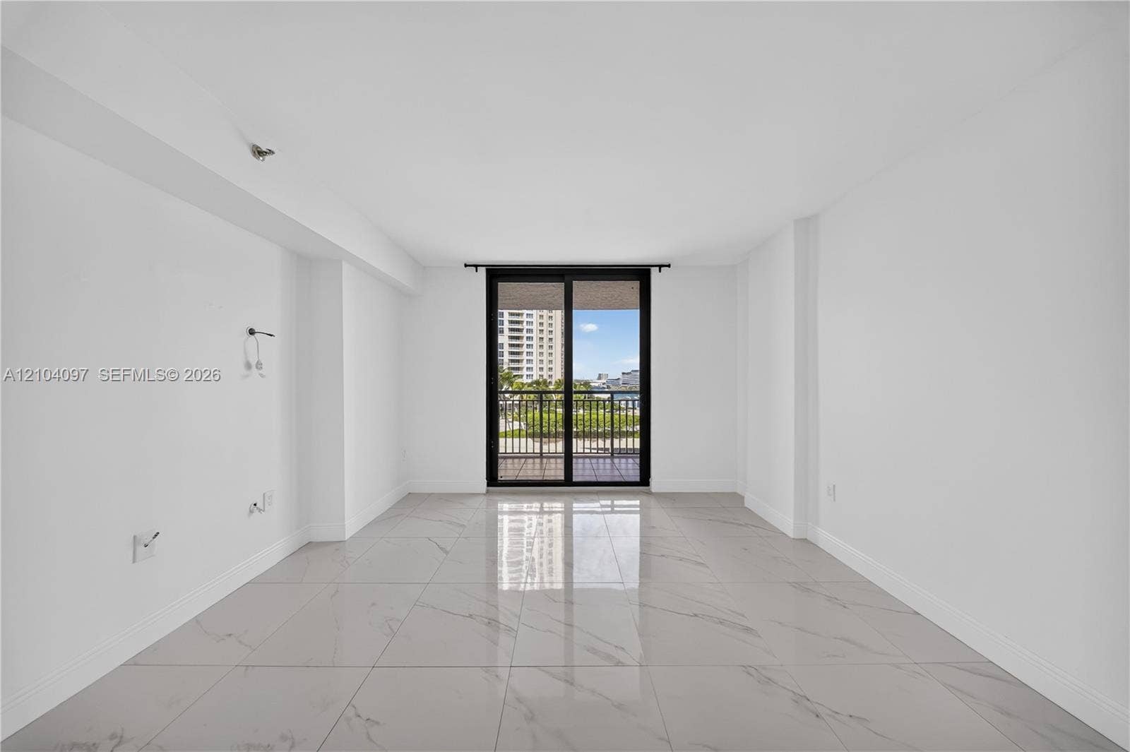 540 Brickell Key Drive, #916, Miami, Miami, FL 33131 Interior room featuring polished large-format stone-style flooring, white walls, and a sliding glass door with a dark metal frame