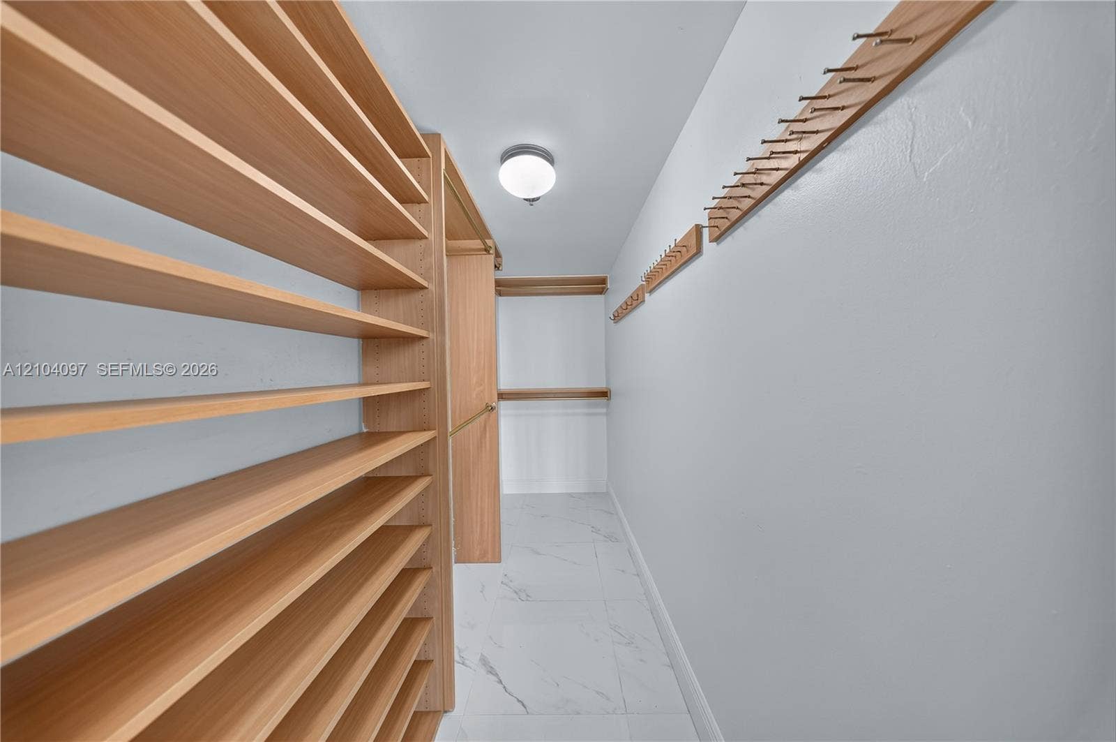 540 Brickell Key Drive, #916, Miami, Miami, FL 33131 Custom storage space featuring extensive wood-finish shelving, wall-mounted hanging racks, and large-format tile flooring