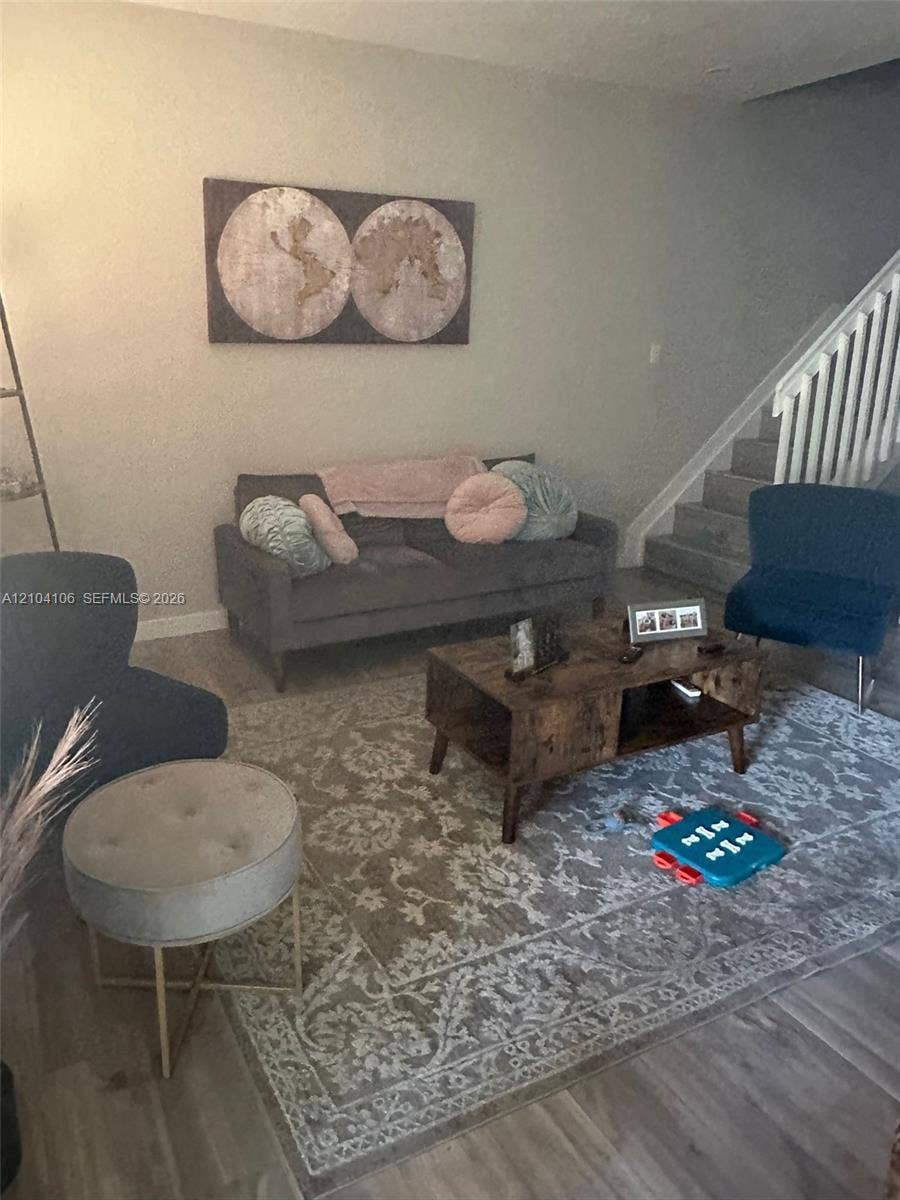 Wood-finish flooring, neutral wall tones, and staircase featuring white vertical balusters
