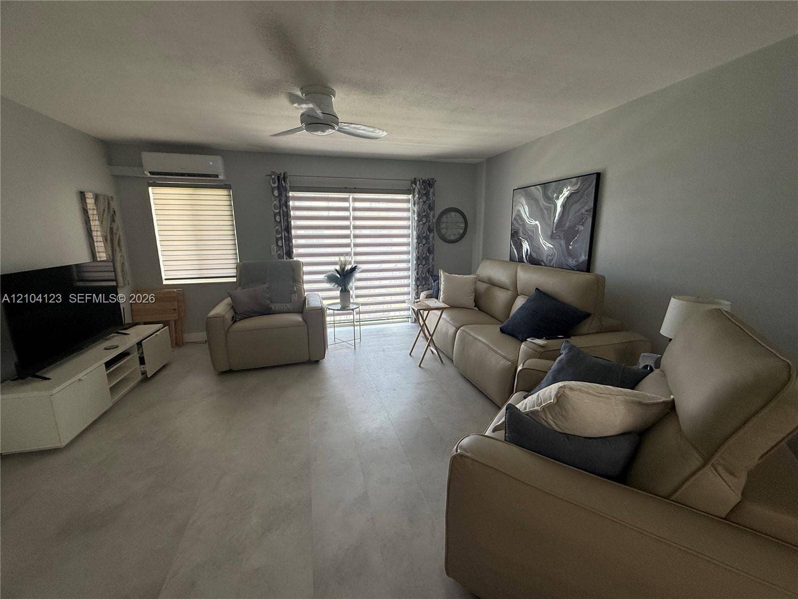 Light gray walls, wood-finish flooring, ceiling fan, window with blinds, and a sliding glass door