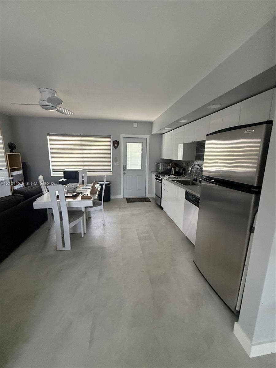 Recessed lighting, stainless steel appliances, contemporary white cabinetry, and light-toned flooring