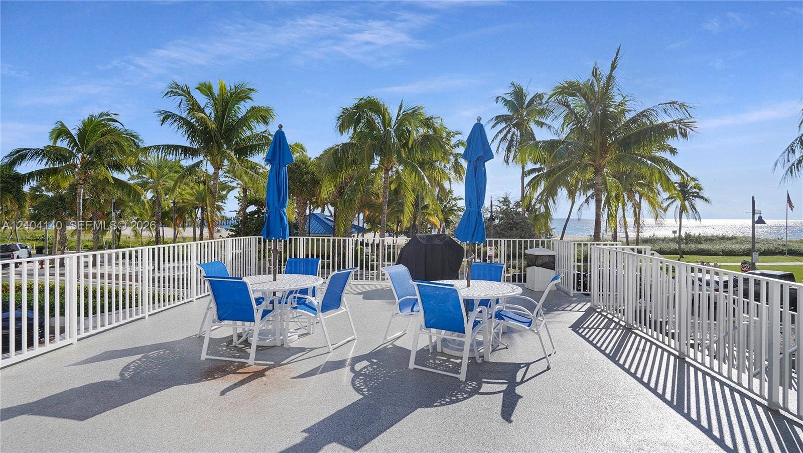111 N Pompano Beach Boulevard, #304, Pompano Beach, FL 33062 Expansive rooftop terrace featuring a textured concrete surface, white metal perimeter railing, and a direct water backdrop